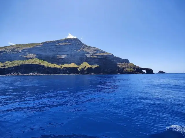 Un promontorio roccioso con l'arco naturale alla base