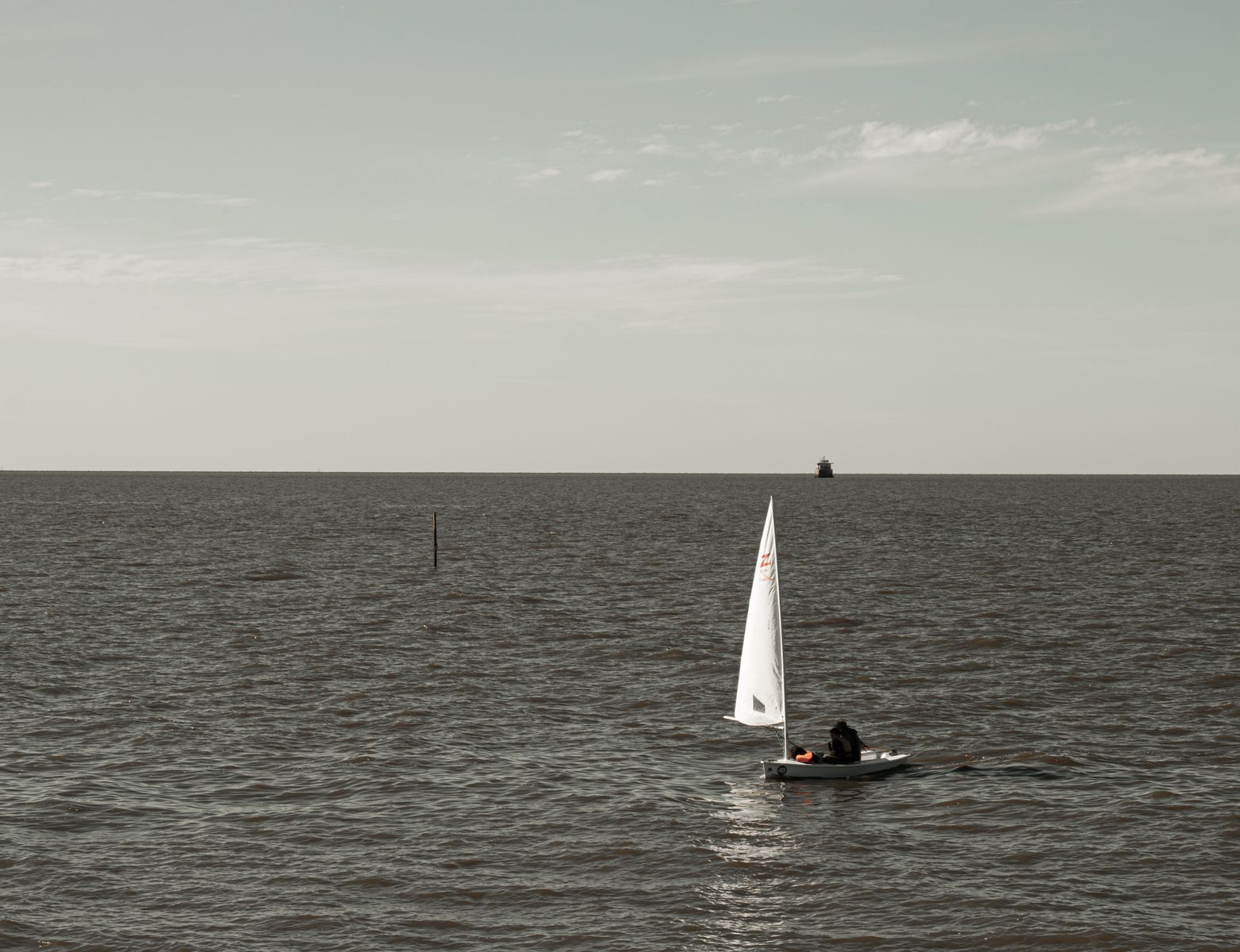 Una barca a vela naviga su un mare calmo sotto un cielo sereno