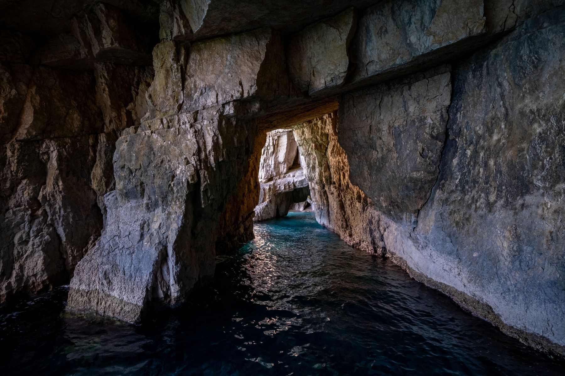 L'interno di una grotta marina con la luce che filtra e i riflessi sull'acqua trasparente